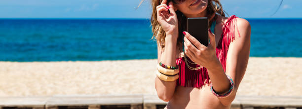 istock Young woman using cellphone on a tropical sandy beach. 1202911245