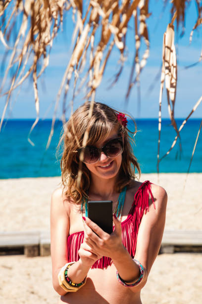 istock Young woman using cellphone on a tropical sandy beach. 1202911351