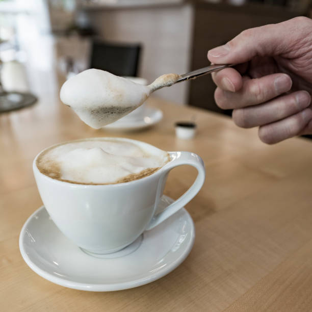 istock cappuccino in white cup and saucer and spoon with foam 1202913085