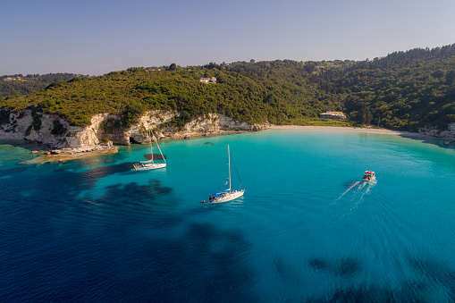 Amazing color of water and landscape on island of Antipaxos, Greece. Sailboat moored in shallow water near beach