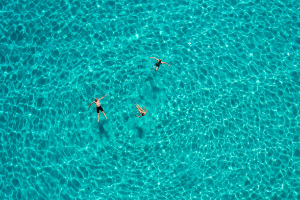 People enjoying swimming at morning in crystal clear water with beautiful color. Famous Voutumni beach, island of Antipaxos, Greece