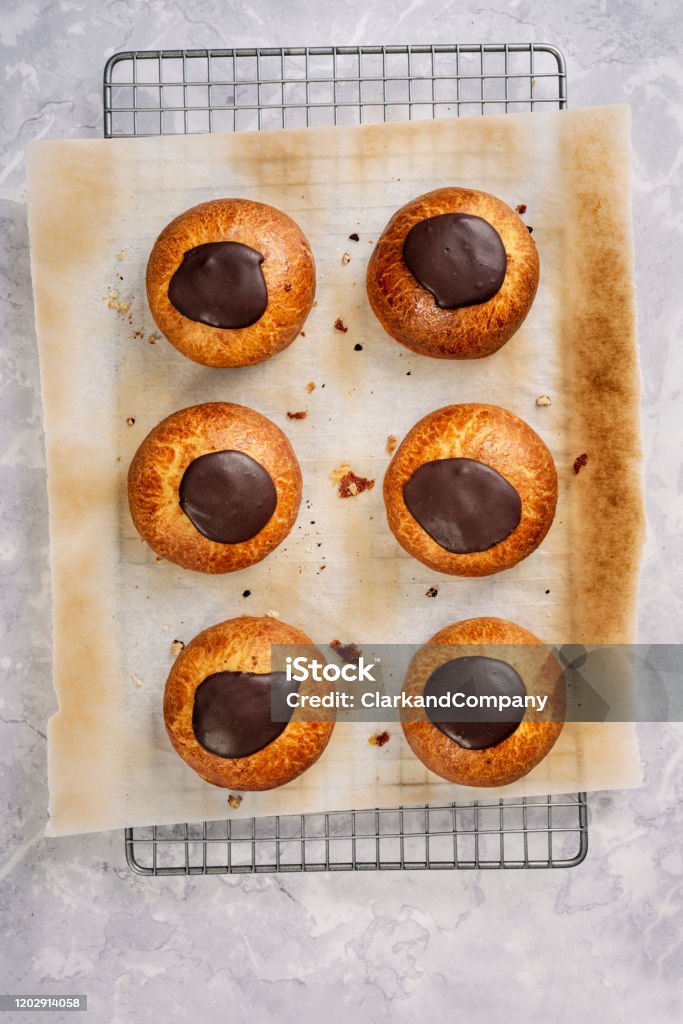 Traditional Old Fashioned Fastelavnboller or Danish Cream Cakes Fastelavnboller or Fastelavn Buns are a Danish delicacy made and eaten in great quantities in the period up to the beginning of Lent in many parts of Scandinavia. These are “Gammeldags Fastelavnboller”  or “Old-fashioned” cream cakes. Made from a simple bread dough recipe with some marzipan filling and topped with melted chocolate. Colour, vertical with copy space.. Baked Stock Photo