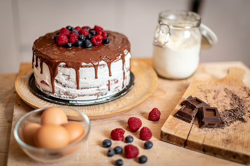 Woman baking at home: Chocolate sponge cake with berries