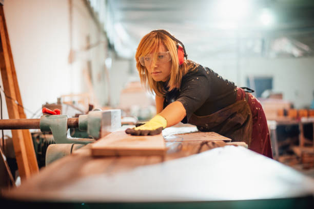istock Woman woodworker using a saw guide to cut a wooden plank on a work bench 1202916277