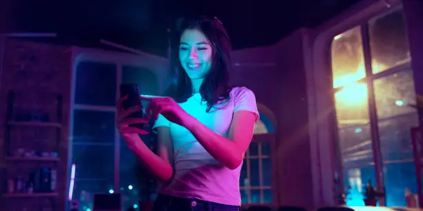 Photo of Cinematic portrait of handsome young woman in neon lighted interior