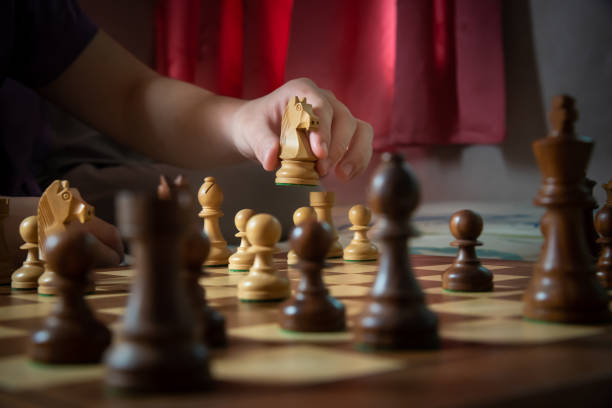 primer plano de la mano mover caballero en posición en el tablero de ajedrez - chess skill concentration intelligence fotografías e imágenes de stock