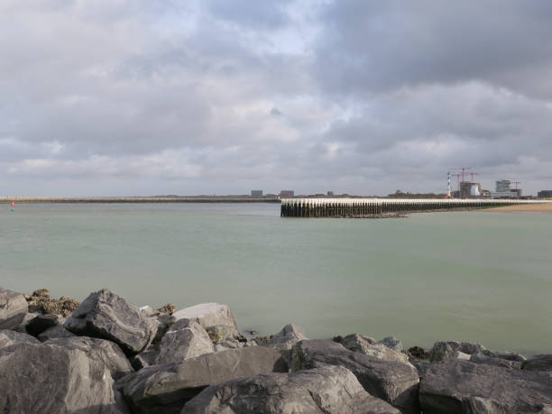 istock pier of Ostend with cloudy sky, cranes and a lighthouse 1202917477