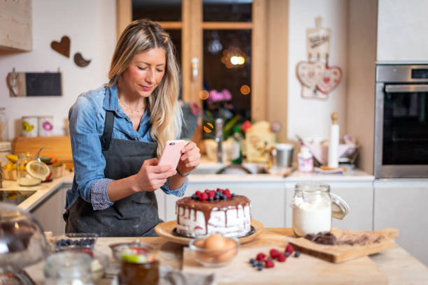 Woman baking at home: Photographing her chocolate sponge cake with berries Woman baking at home: Photographing her chocolate sponge cake with berries chocolate cake photos stock pictures, royalty-free photos & images