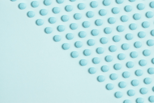 Blue pills on light blue background with copy space