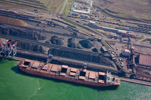 Coal terminal. Open warehouses with coal, ore, stacks. Loading using conveyor equipment, ship-loading machines. Delivery of goods by rail