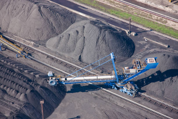 istock Stacks of coal, ore, bentonite. Cargo transshipment is carried out by a stacker, a reclaimer and railroad cars. 1202919028