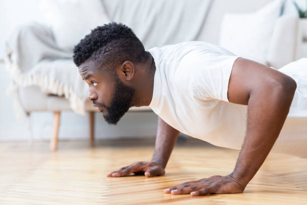 Young black man doing push ups, side view Young black man exercising in his house gym, doing push ups, side view, free space push ups stock pictures, royalty-free photos & images
