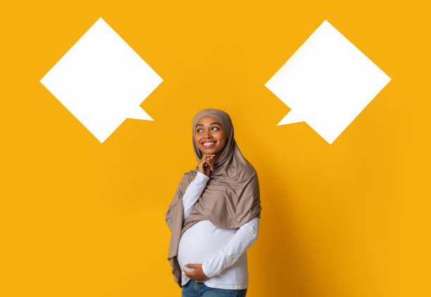 istock Happy pregnant black muslim woman choosing between two empty speech bubbles 1202920891
