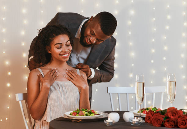 homme africain de gallant mettant le collier d'or sur sa femme - anniversary couple rose black photos et images de collection