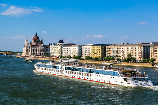A luxury river boat,  sails past the inpressive Hungarian House of Parliament on the Danube River.