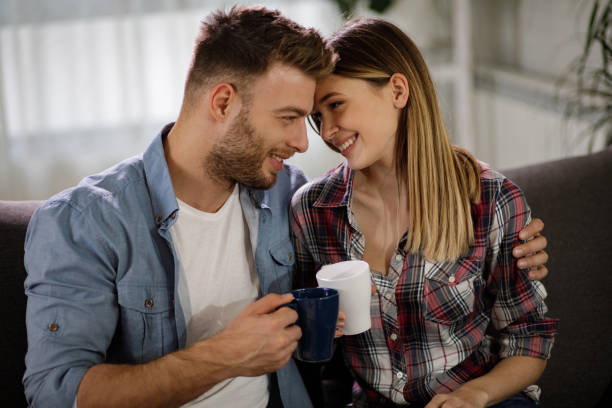 istock Affectionate couple relaxing together at home with cup of coffee 1202923542