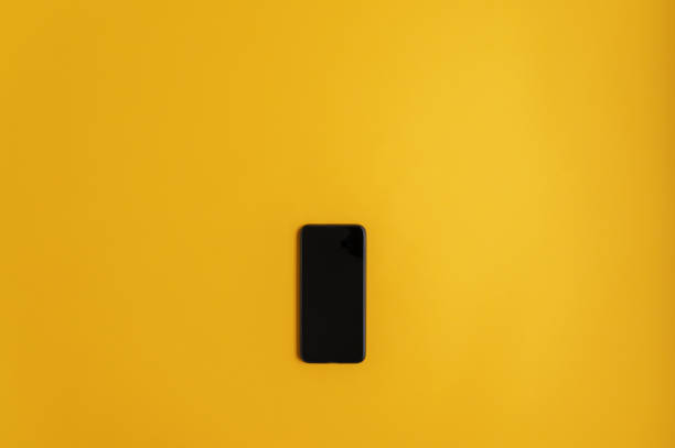 istock Black smart phone over yellow background 1202923565