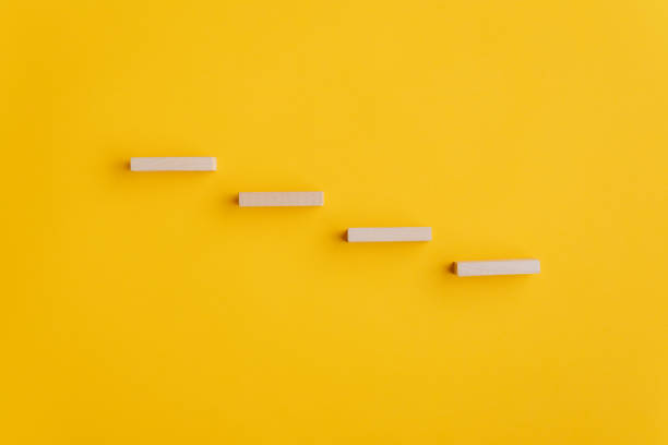 istock Four blank wooden pegs placed in a stairway like structure 1202923910