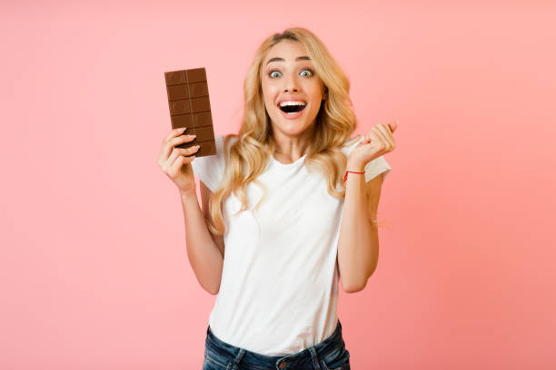 istock Chocolate lover. Overjoyed girl holding choco bar 1202924153