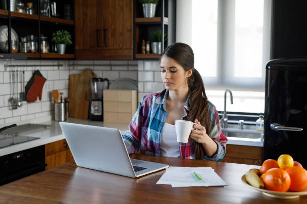 istock Pregnant woman sitting in kitchen and working on laptop computer 1202924178