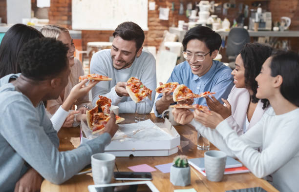 istock Positive business team eating pizza in office 1202925044