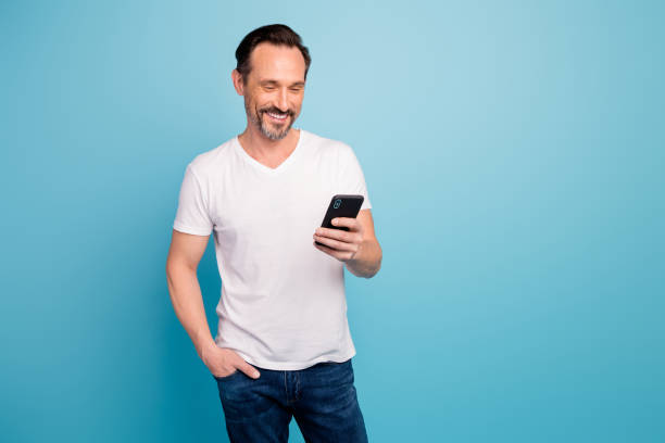 istock Portrait of his he nice attractive cheerful cheery content guy IT freelancer checking reading sms task salary isolated on bright vivid shine vibrant teal green blue turquoise color background 1202928260