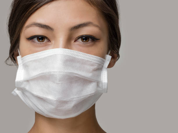 Young woman wearing medical face mask, studio portrait Young woman wearing medical face mask, studio portrait obscured face photos stock pictures, royalty-free photos & images