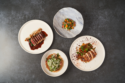 Set of various plates of food on a gray table background with copy space. Assorted food set served on restaurant table. Variety of Healthy diet food