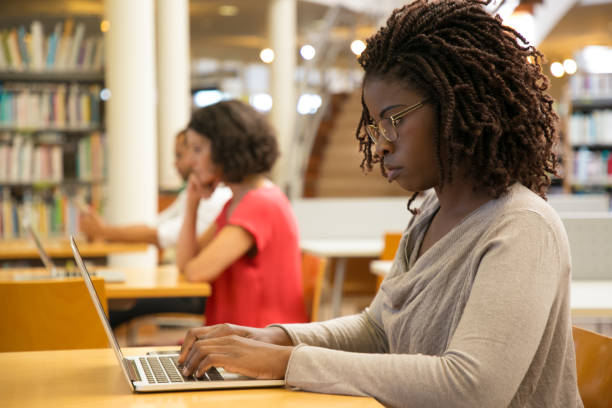 istock Side view of thoughtful woman working with laptop at library 1202951248