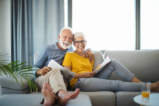 mature couple reading newspapers on a weekend afternoon. - window home interior women people imagens e fotografias de stock