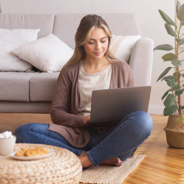 istock Charming freelancer working on laptop, sitting on floor 1202951945
