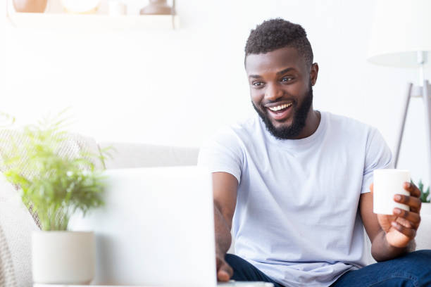 istock Young african guy having video chat with friends on laptop 1202952201