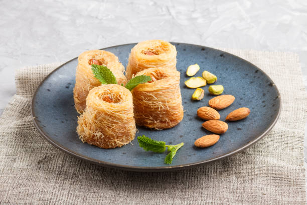 Kunafa, traditional arabic sweets in blue ceramic plate on a gray concrete background. side view, close up.
