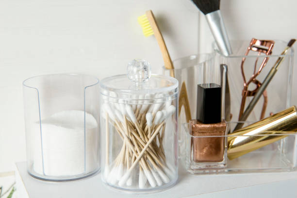 Make up products organizing concept. Beauty products in organizer container box on tidy way on minimalist shelf. Cotton pads stacked, Q-tips and make up brushes.