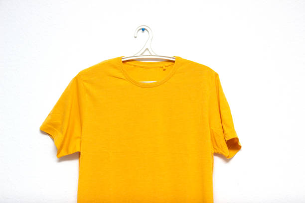 istock Blank Yellow t-shirt hanging mock up on white wall, front view. 1202954932