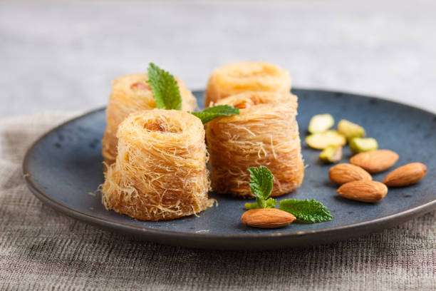 istock Kunafa, traditional arabic sweets in blue ceramic plate on a gray concrete background. side view, close up, selective focus. 1202954951