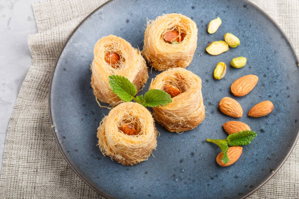 istock Kunafa, traditional arabic sweets in blue ceramic plate on a gray concrete background. side view, close up. 1202955098