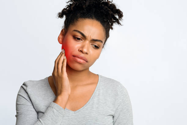 Woman suffering from inflamed gums, grey background Dental problems. Afro woman suffering from inflamed gums, touching her cheek, grey background, free space jaw pain stock pictures, royalty-free photos & images