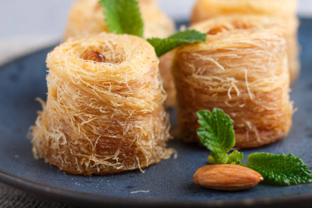 istock Kunafa, traditional arabic sweets in blue ceramic plate on a gray concrete background. side view, close up, selective focus. 1202956135