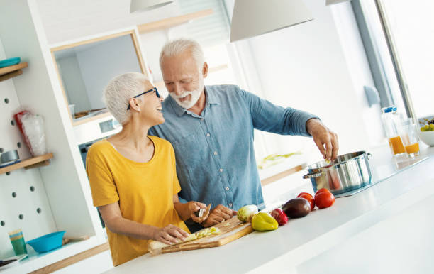 mature couple cooking lunch together. - cooking senior adult healthy lifestyle couple imagens e fotografias de stock