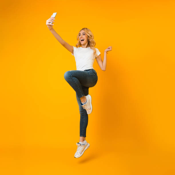 istock Crazy girl jumping up and making selfie on phone 1202956564