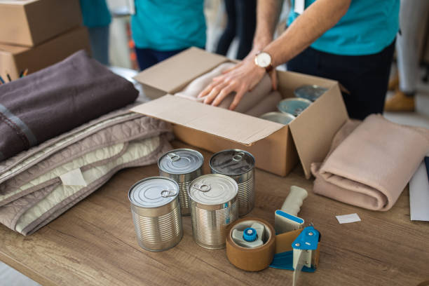 istock Young man working at charitable foundation, packing donation box 1202956878
