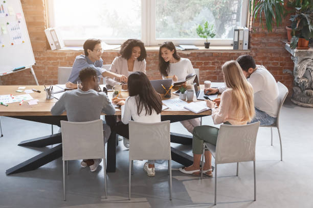 istock Friendly business team sitting around table, having meeting 1202957837
