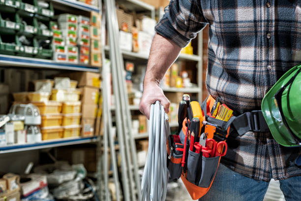 Electrician in the store of electrical components. Electricity. Electrician in the electrical parts store is holding the roll of electrical cable. Construction industry, electrical system. warehouse tools stock pictures, royalty-free photos & images