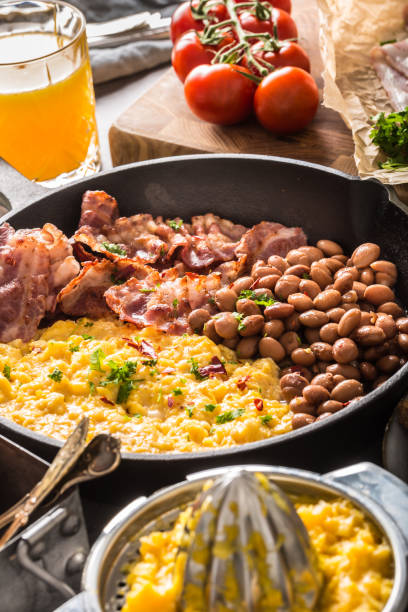 Full table of english breakfast. Scrambled eggs grilled bacon beans toast bread orange juice and coffee