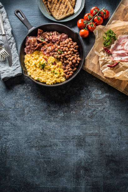 English breakfast scrambled eggs grilled bacon beans and toast bread - Top of view