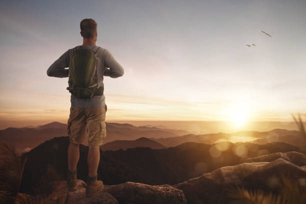 istock Young man enjoying the sunset over a mountain range 1202958933