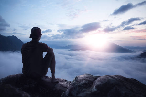 istock Young man enjoying the sunrise on a mountain peak 1202958940