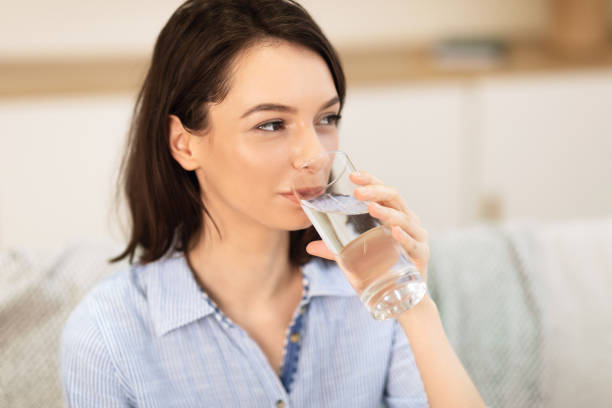 istock Smiling girl drinking clean water from glass 1202959426