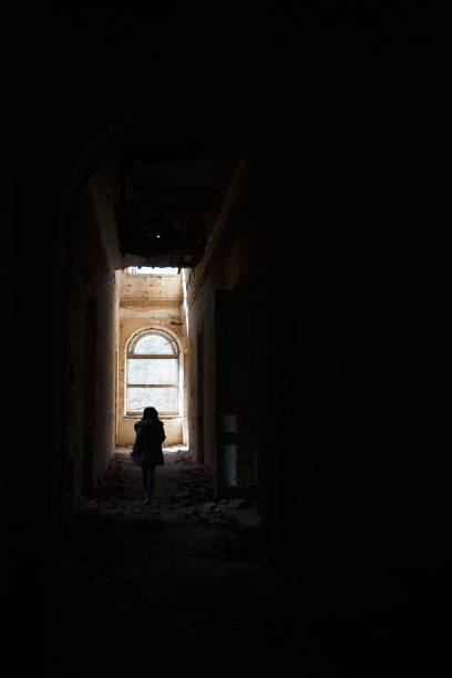 istock A man at the end of a dark corridor inside an abandoned building. 1202959706